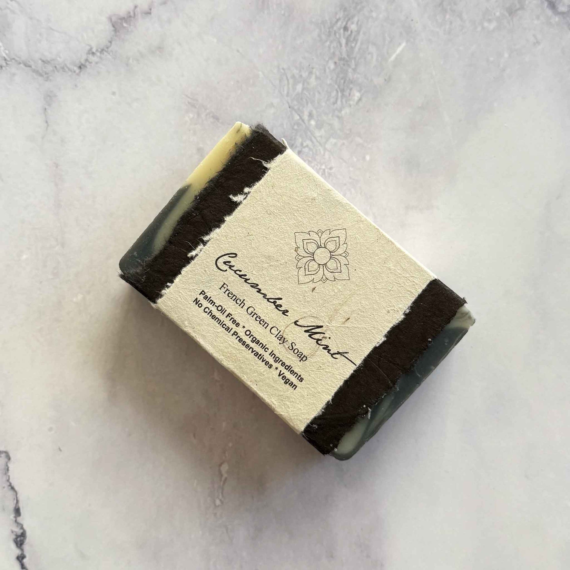 Handmade Cucumber Mint soap bar with a flower seed paper label on a marble surface