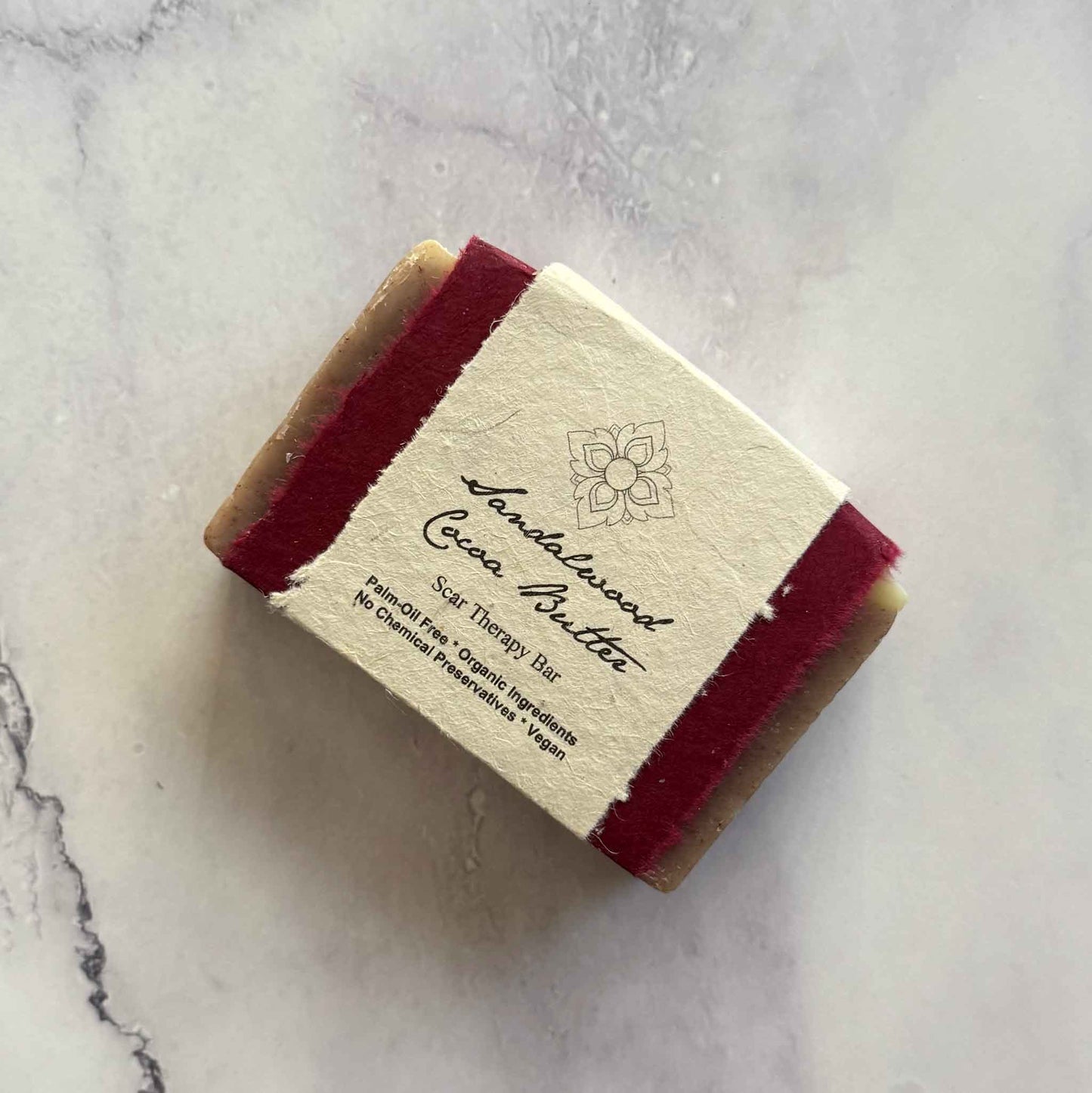 Handmade Sandalwood Cocoa Butter soap bar with a flower seed paper label on a marble surface