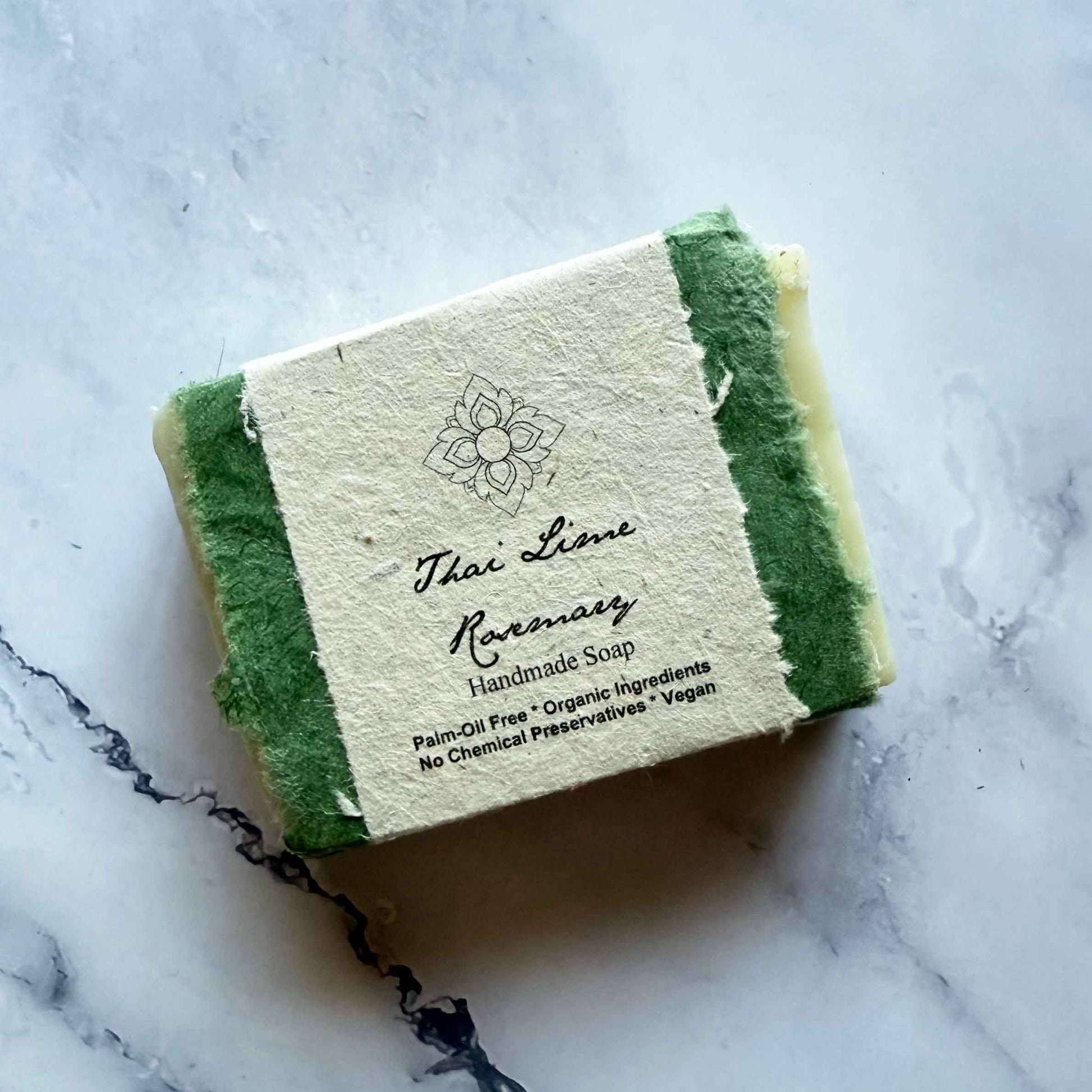 Handmade Thai Lime Rosemary soap bar with a flower seed paper label on a marble surface